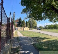 Veľký pozemok na výstavbu v centre Bernolákova. - Chodník vedie popri plote v záhradách Bernolákova, s cestou na pozadí.
