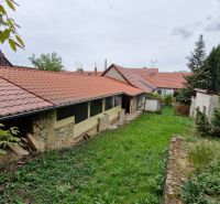 Mokrý Háj - predaj dom - Záhrada pri rodinnom dome v Mokrém Háji s kamenným múrom a červenou strešnou krytinou.