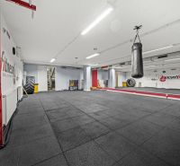Na predaj PRIESTRANNÉ FITNESS CENTRUM na LUKRATÍVNEJ ADRESE RUŽINOVA - Fitness priestor s boxovacím vrecom, veľkými zrkadlami a čiernou podlahou.