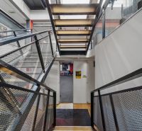 Na predaj PRIESTRANNÉ FITNESS CENTRUM na LUKRATÍVNEJ ADRESE RUŽINOVA - Chodba s kovovým schodiskom a mrežovým zábradlím v obchodných priestoroch.