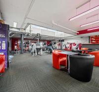 Na predaj PRIESTRANNÉ FITNESS CENTRUM na LUKRATÍVNEJ ADRESE RUŽINOVA - Obchodné priestory s posilňovacími strojmi a červenými koženými kreslami.
