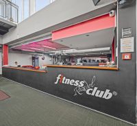 Na predaj PRIESTRANNÉ FITNESS CENTRUM na LUKRATÍVNEJ ADRESE RUŽINOVA - Recepcia fitness klubu s nápisom, červeným osvetlením a dekoratívnymi trofejami na zemi zeleného odtieňa.