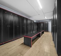 Na predaj PRIESTRANNÉ FITNESS CENTRUM na LUKRATÍVNEJ ADRESE RUŽINOVA - Čierne skrinky, lavice s kontrastným dizajnom, podlaha s dreveným dekorom v obchodných priestoroch.