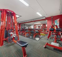 Na predaj PRIESTRANNÉ FITNESS CENTRUM na LUKRATÍVNEJ ADRESE RUŽINOVA - Fitness centrum s červenými posilňovacími strojmi a činkami, obchodné priestory.