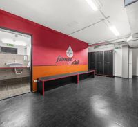 Na predaj PRIESTRANNÉ FITNESS CENTRUM na LUKRATÍVNEJ ADRESE RUŽINOVA - Šatňa s čiernymi skrinkami, lavicou a vstupom do kúpeľne v obchodných priestoroch.