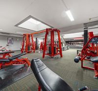 Na predaj PRIESTRANNÉ FITNESS CENTRUM na LUKRATÍVNEJ ADRESE RUŽINOVA - Fitness centrum s posilňovacími strojmi a červenými lavičkami, vhodné obchodné priestory.