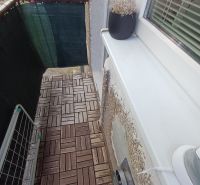 Krásny 2 izbový byt s balkónom- Vargové pole. - Balkón v 2-izbovom byte s podlahou s dreveným dekorom a kvetináčom.