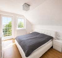 6-izbový rodinný dom v Šamoríne | 201 m² | pozemok 451 m² | - Spálňa v rodinnom dome s veľkým oknom a podlahou s dreveným dekorom.