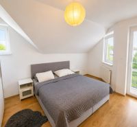 6-izbový rodinný dom v Šamoríne | 201 m² | pozemok 451 m² | - Spálňa so strešnými oknami, sivou posteľou a podlahou s dreveným dekorom v rodinnom dome.