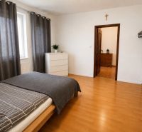 6-izbový rodinný dom v Šamoríne | 201 m² | pozemok 451 m² | - Spálňa v rodinnom dome s posteľou, komodou a podlahou s dreveným dekorom.