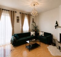 6-izbový rodinný dom v Šamoríne | 201 m² | pozemok 451 m² | - Obývačka v rodinnom dome s tmavozelenou sedačkou, kozubom a veľkými oknami.