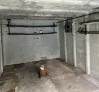 18 m2 Garáž na Sliačskej ulici v Bratislave - Betónová miestnosť s držiakmi na stene a podlahou s dreveným dekorom v garážach.