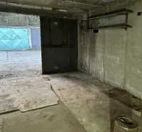 18 m2 Garáž na Sliačskej ulici v Bratislave - Interiér garáže s betónovou podlahou a kovovými regálmi.