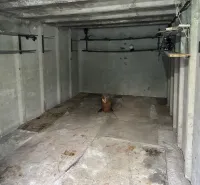 18 m2 Garáž na Sliačskej ulici v Bratislave - Interiér garáže s betónovými stenami a policami na ukladanie vecí.
