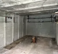 18 m2 Garáž na Sliačskej ulici v Bratislave - Prázdna betónová miestnosť s trubkami a osvetlením, interiér garáže.