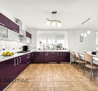 Na predaj 9-izb. RD v obci Nový Život - Vojtechovce - Kuchyňa v rodinnom dome s bordovými skrinkami a podlahou s dreveným dekorom.