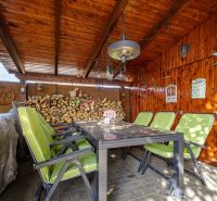 4 izbový rodinný dom Nová Dedinka, predaj, 543m2  - Drevený altánok s kamennou podlahou a zelenými stoličkami pri rodinnom dome.