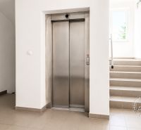Slnečný 2-izb. byt, terasa a balkón, Stupava, V. Šikulu - Chodba s výťahom a schodmi vedúcimi k oknu, 2-izbový byt.