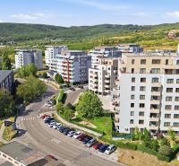 Zariadený 2-izbový byt s loggiou na Kadnárovej ulici - Pohľad na obytné budovy na Kadnárovej ulici v Bratislava - Rača obklopené zeleňou.