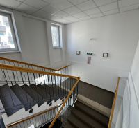 Zariadený 1-izbový byt na predaj, Podunajské Biskupice - Schodisko s oknami a zábradlím v budove na ulici Podunajská, Bratislava - Podunajské Biskupice.