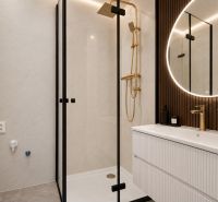NA PREDAJ ŠTÝLOVÝ A VEĽKÝ 3-IZBOVÝ BYT, KOMPLETNÁ REK., LAMAČ - BA - Kúpeľňa v 3-izbovom byte s elegantnou sprchou, zlatými detailmi a osvetleným zrkadlom.