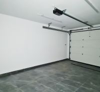 / Novostavba, moderný bungalov, dokončený na kľúč  - Garáž v rodinnom dome s dlažbou, automatickou bránou a svetlými stenami.
