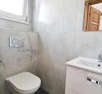 / Novostavba, moderný bungalov, dokončený na kľúč  - Kúpeľňa v rodinnom dome s podlahou s dreveným dekorom a bielym sanitárnym vybavením.