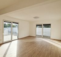 / Novostavba, moderný bungalov, dokončený na kľúč  - Obývačka rodinného domu s podlahou s dreveným dekorom a veľkými oknami na terasu.