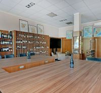 Klimatizovaný obchodný priestor - showroom alebo klinika,vstup z ulice - Interiér obchodných priestorov s regálmi na vína a podlaha s dreveným dekorom.