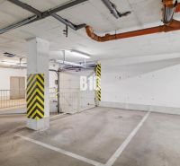 PRIESTRANNÝ 4-IZBOVÝ BYT S DVOMA BALKÓNMI | KRAMÁRE – ul. UHROVA - Podzemné parkovacie státie v 4-izbovom byte so žltými bezpečnostnými pruhmi a potrubiami.