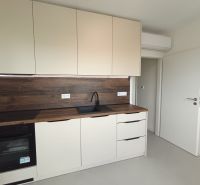 ? Na prenájom: moderný 2 izbový byt – Residence Majakovského, Lučenec - Kuchyňa v 2-izbovom byte s bielymi skrinkami a podlahou s dreveným dekorom.