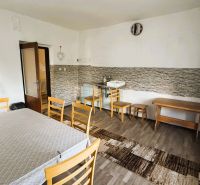 Dve generácie pod jednou strechou, Novosad, rodinný dom, 99.000€ - Jedáleň v rodinnom dome s dreveným dekorom podlahy, jednoduchým nábytkom a umývadlom.