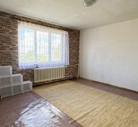 Dve generácie pod jednou strechou, Novosad, rodinný dom, 99.000€ - Izba s veľkým oknom, kobercom a tehlovým vzorom stien v rodinnom dome.