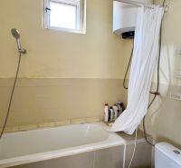 Dve generácie pod jednou strechou, Novosad, rodinný dom, 99.000€ - Kúpeľňa s vaňou, sprchou, bojlerom a podlahou s dreveným dekorom v rodinnom dome.