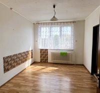 Dve generácie pod jednou strechou, Novosad, rodinný dom, 99.000€ - Izba v rodinnom dome s podlahou s dreveným dekorom, závesom a radiátorom pod oknom.