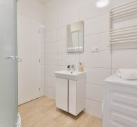 MINÚTU OD NÁMESTIA - VEĽKÁ GARSÓNKA V CENTRE - Kúpeľňa v garsónke s podlahou s dreveným dekorom, bielymi obkladačkami a sprchovým kútom.