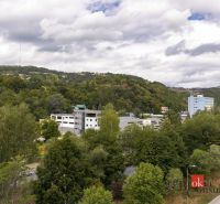 Na predaj luxusný 2-izbový byt, výnimočná terasa pre náročných - Výhľad na zeleň a budovy v Banskej Bystrici na Severnej ulici, obklopené kopcami.