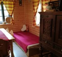 Dva vidiecke domy na pozemku 1,6ha D. Strehová (Prieloh), V. Krtíš. - Interiér drevenice s masívnym nábytkom, drevenými stenami a farebnými závesmi v rodinnom dome.