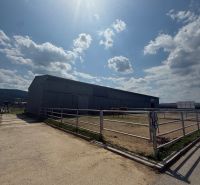 Plechová Hala na predaj Hniezdne - Budova v Hniezdnom, oplotený priestor s koňmi, slnečná obloha, mierne oblačno.