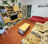 4 izbový byt Bánovce nad Bebravou /CENTRUM - STRED / 80 m2/ PIVNICA - Obývacia izba v 4-izbovom byte so sedačkou, červeným sedacím zákutím a stenovou policou.