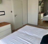 2-izb. byt Pri Hrubej lúke v projekte Tammi, pivnica, garážové státie - Spálňa v 2-izbovom byte s bielou posteľou a podlahou s dreveným dekorom.