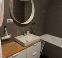 2-izb. byt Pri Hrubej lúke v projekte Tammi, pivnica, garážové státie - Kúpeľňa v 2-izbovom byte s umývadlom, zrkadlom a vaňou, elegantné hnedé obklady.