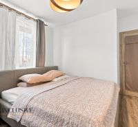 Na predaj moderný 3-izbový radový rodinný dom, Oľdza - Spálňa v rodinnom dome s podlahou s dreveným dekorom, sivou posteľou a závesmi.