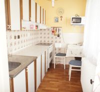 Rodinný dom v BA IV - Záhorská Bystrica, ul. Donská - Kuchyňa v rodinnom dome s podlahou s dreveným dekorom, jedálenským stolom a spotrebičmi.