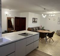 Priestranný a kvalitne zariadený 3-izbový byt – Bratislava, Petržalka - Obývačka s jedálenským stolom a kuchyňou v 3-izbovom byte, podlaha s dreveným dekorom.