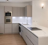 Priestranný a kvalitne zariadený 3-izbový byt – Bratislava, Petržalka - Kuchyňa v 3-izbovom byte s podlahou s dreveným dekorom a modernými spotrebičmi.