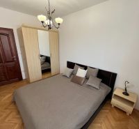 Priestranný a kvalitne zariadený 3-izbový byt – Bratislava, Petržalka - Spálňa s posteľou, skriňou a podlahou s dreveným dekorom v 3-izbovom byte.