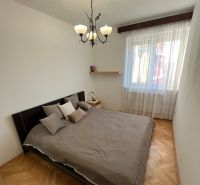 Priestranný a kvalitne zariadený 3-izbový byt – Bratislava, Petržalka - Spálňa v 3-izbovom byte s podlahou s dreveným dekorom, veľkým oknom a lustrom.