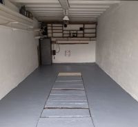 Garáž Púpavova, Karlova Ves + pivnica - Garáž s bielymi stenami a výraznou podlahou na ulici Púpavová, ideálne pre skladovanie.