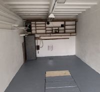 Garáž Púpavova, Karlova Ves + pivnica - Prázdna garáž na ulici Púpavová s úložným priestorom, podlahou a elektrickým napájaním.
